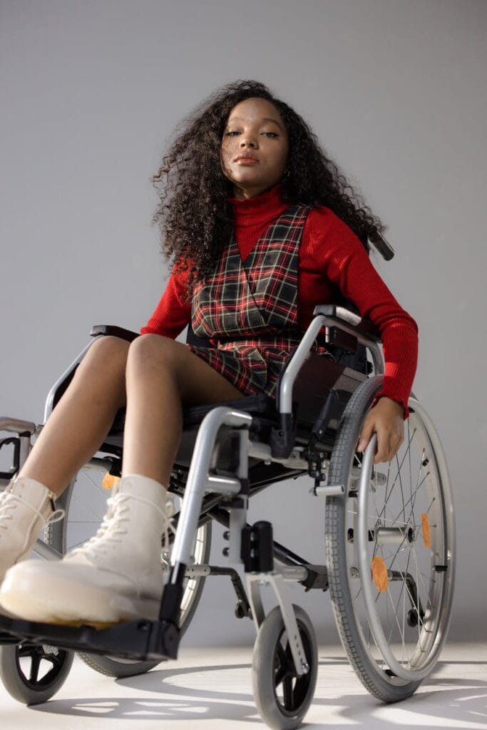 a low angle shot of a woman in red long sleeves sitting on the wheelchair