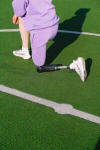 crop woman with leg prosthesis training on stadium