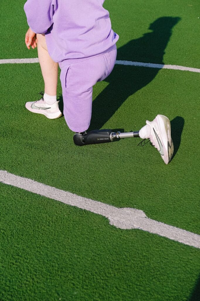 crop woman with leg prosthesis training on stadium